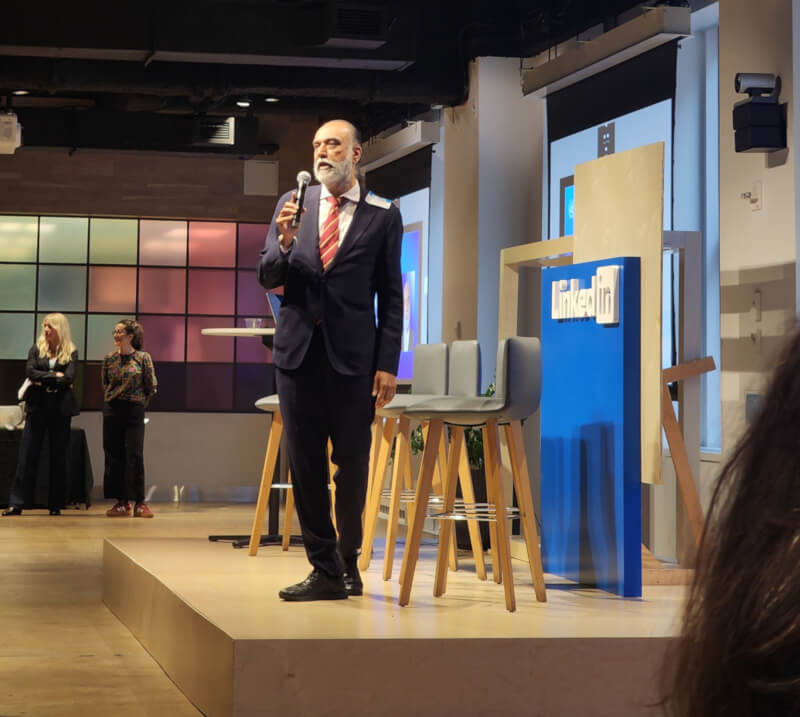 A man speaking on stage during the "AI and the Future of Work" discussion, with the LinkedIn logo visible in the background.